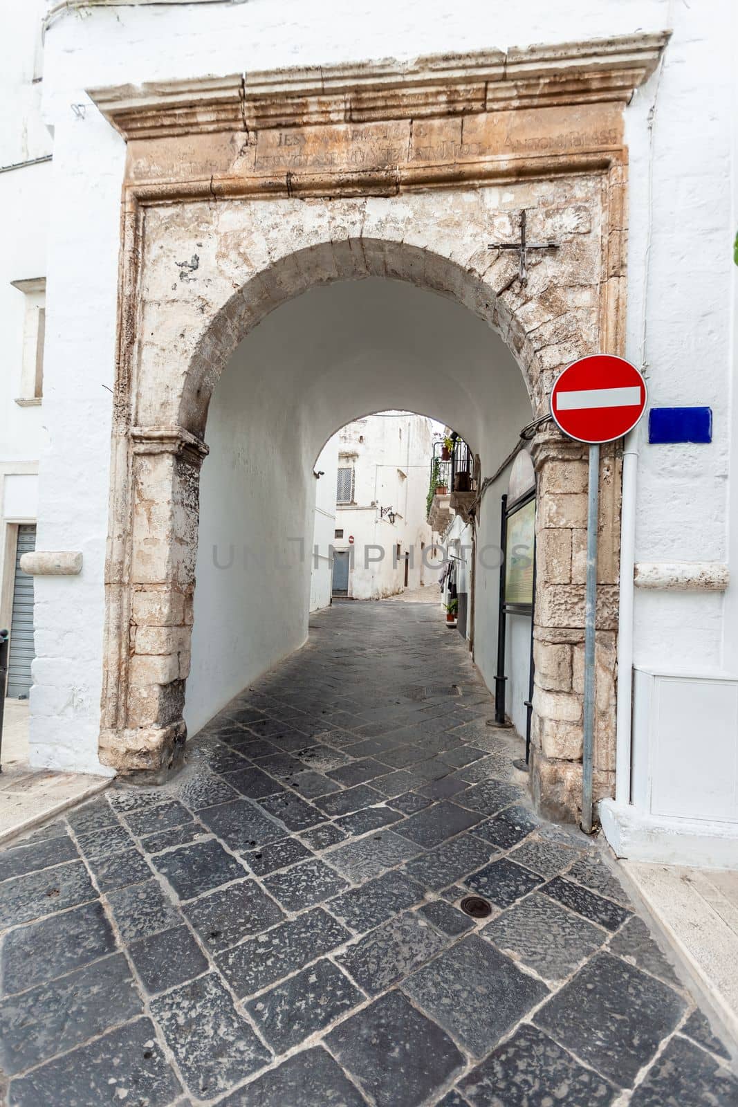 View of the empty streets of old town Martina Franca with a beautiful houses painted in whiteand a stop sign. Wonderful day in a tourist town, Apulia, Southern Italy.