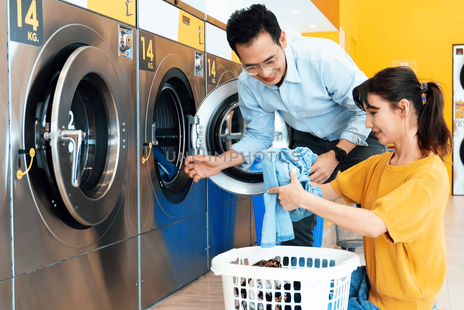 Asian people using qualified coin operated laundry machine in the public room to wash their cloths. Concept of a self service commercial laundry and drying machine in a public room.