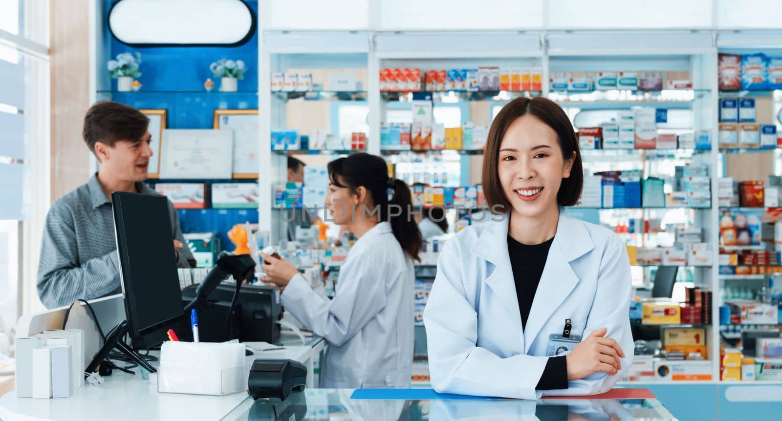 Portrait of affable asian pharmacist and qualified pharmaceutical, medicine pill bottle on shelf in background at pharmacy. Concept of pharmacist working on cashier talking to customer in drugstore.