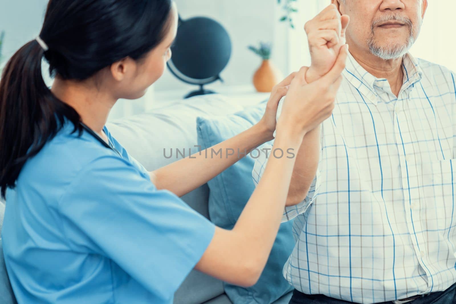 Caring young female doctor performing osteopathy treatment for a contented senior patient. At-home medical treatment for an Asian senior patient, joint pain treatment, medical service for seniors.