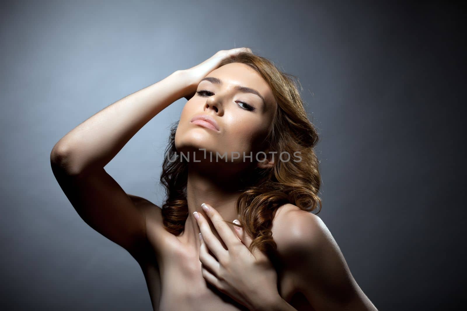 Desired young woman with curly hairs posing topless