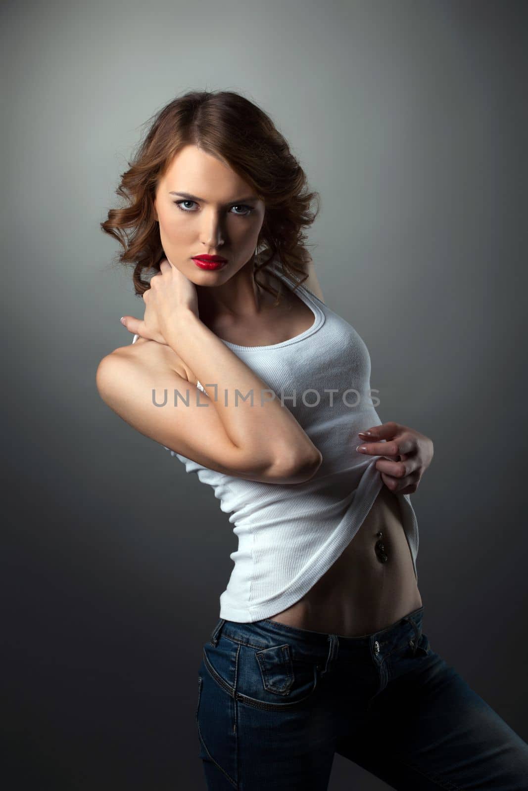 Young beautiful brunette woman in jeans and white tank top