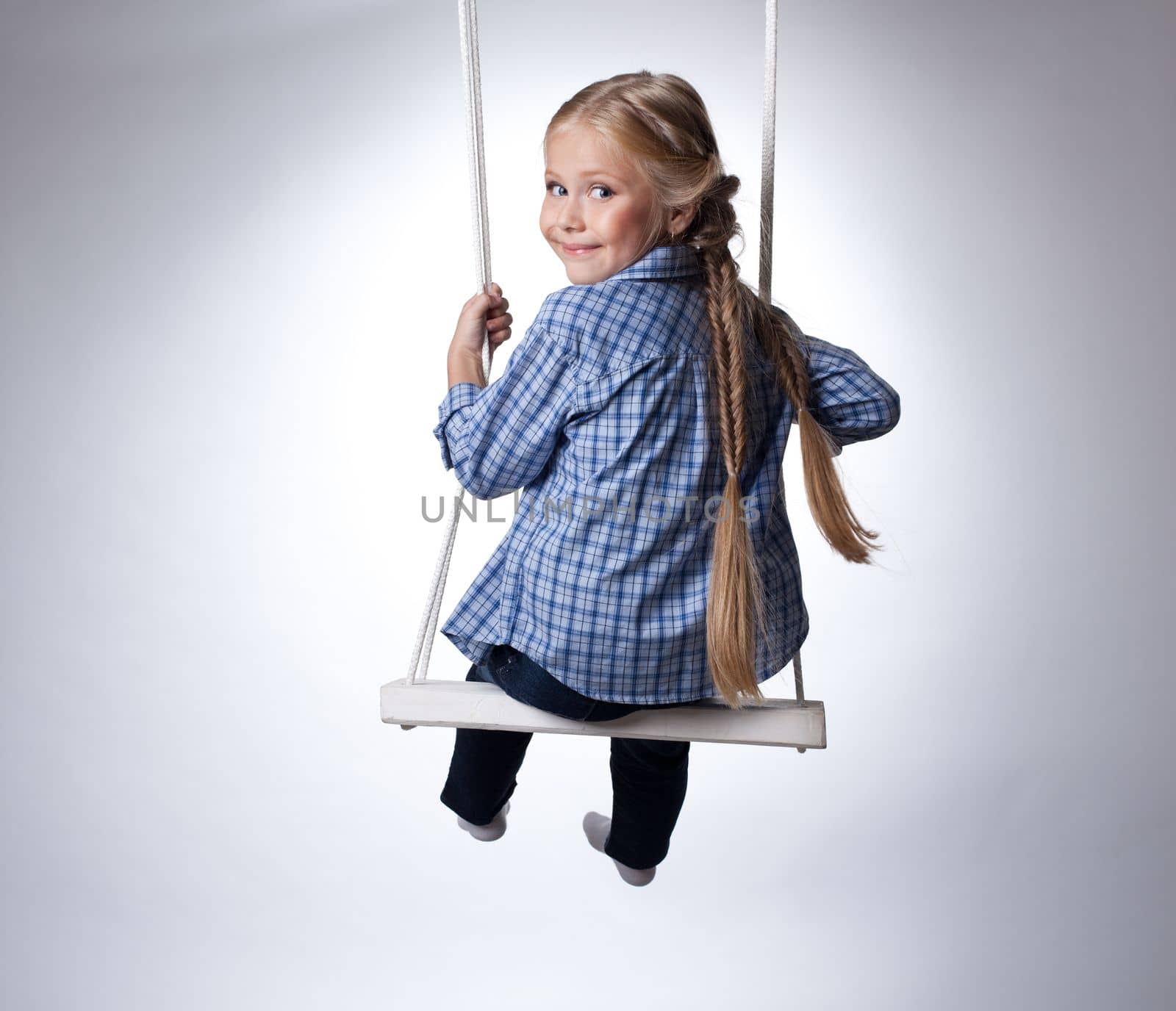 Studio portrait of beautiful blonde girl on swing