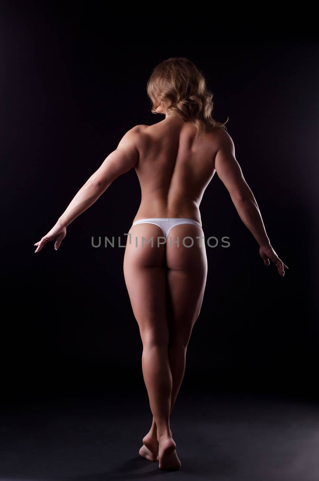 Beauty woman body builder in white panties posing in dark