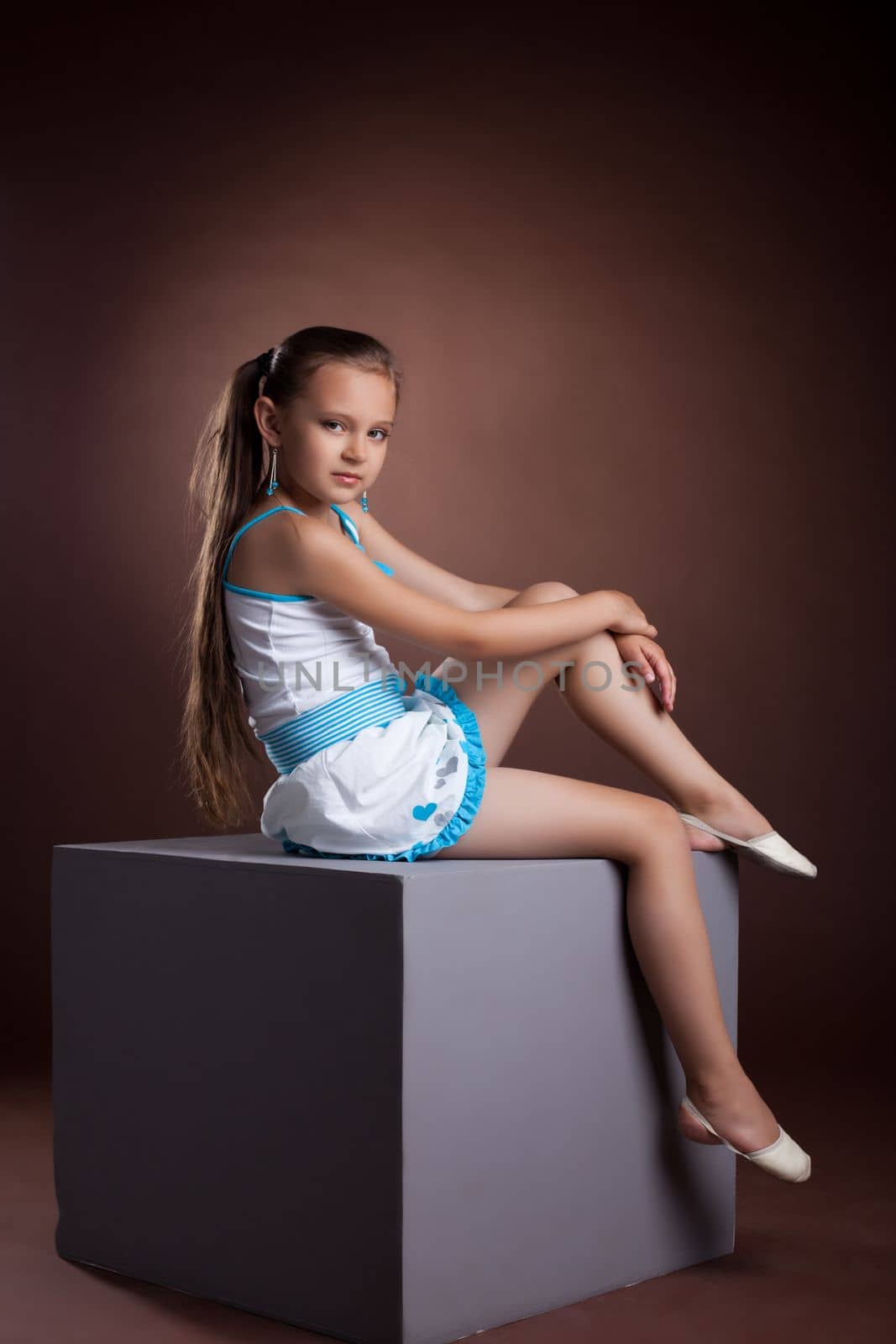 Young child in studio posing on grey cube