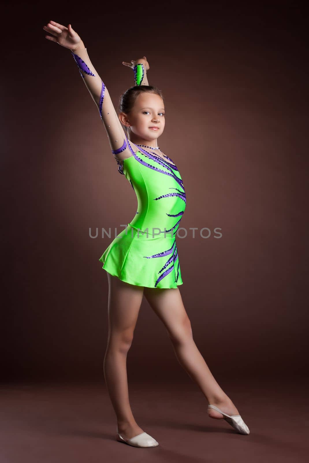 Beauty kid gymnast training in studio - green costume
