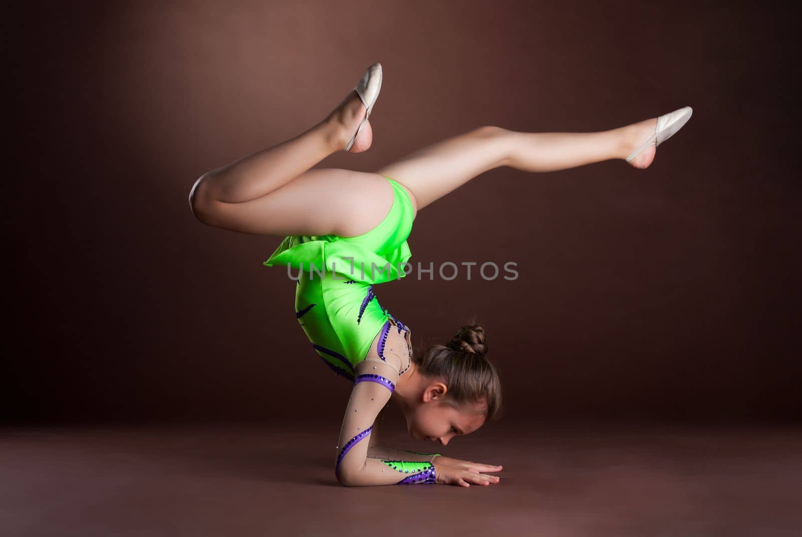small girl gymnast stand on hands in green costume