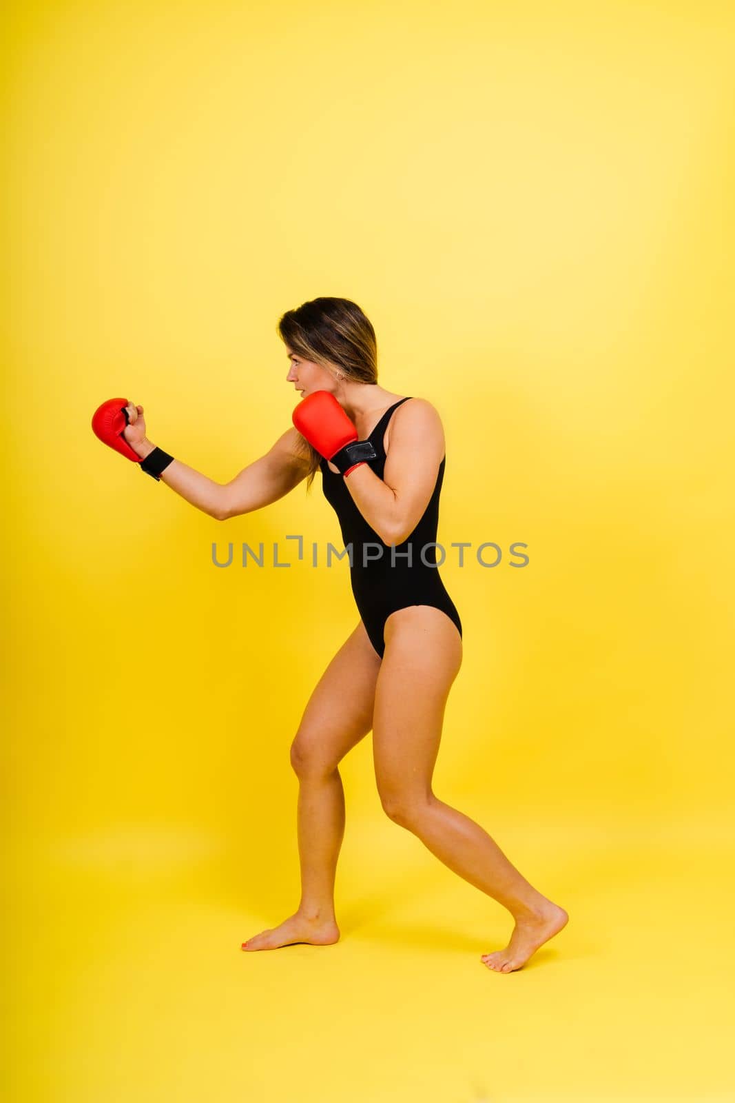 Woman Boxer In Gloves Training On a black, red, yellow Background