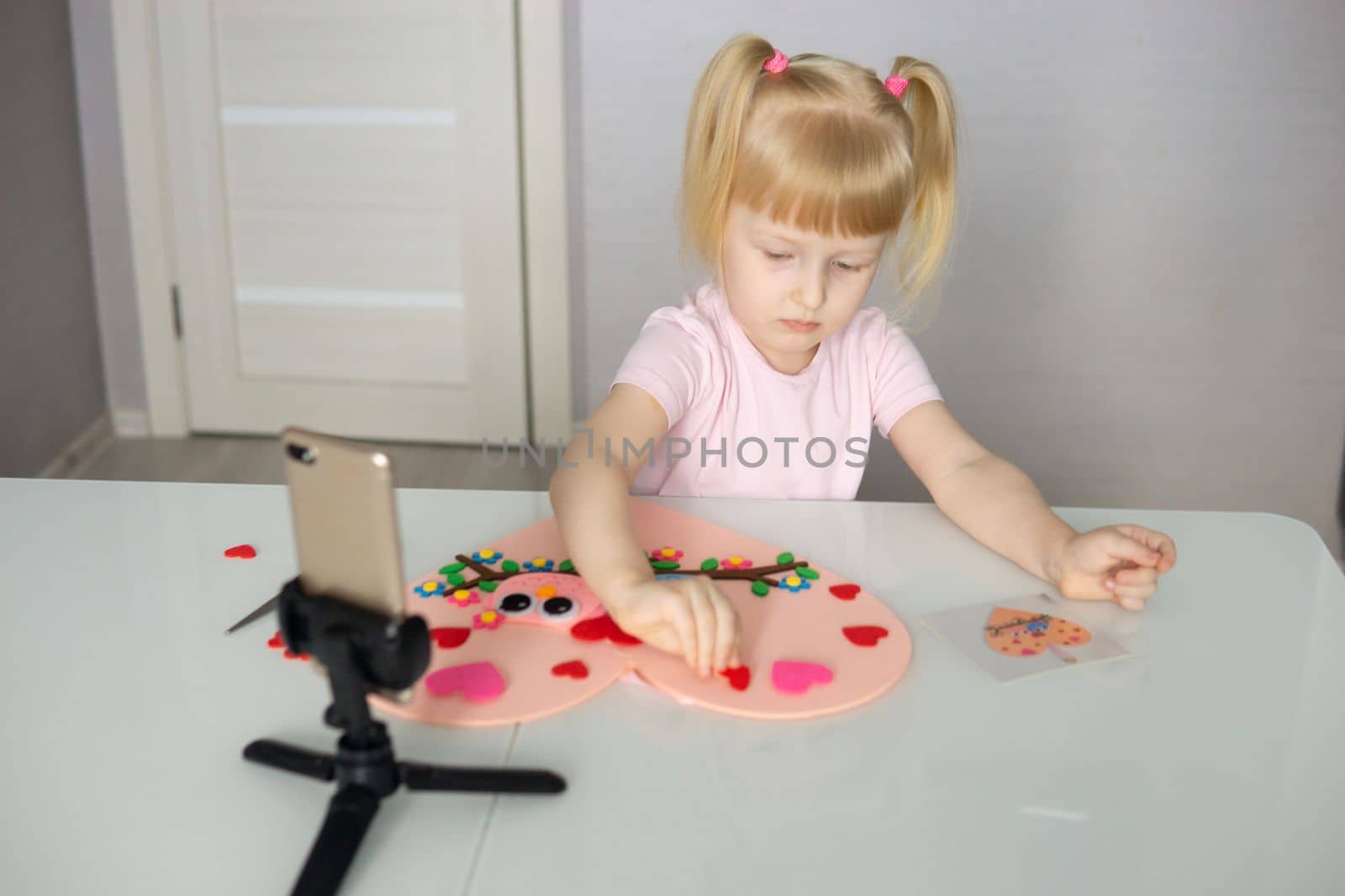 A blogger girl makes a felt craft for Valentine's Day in the shape of a heart. The concept of children's creativity and handmade.