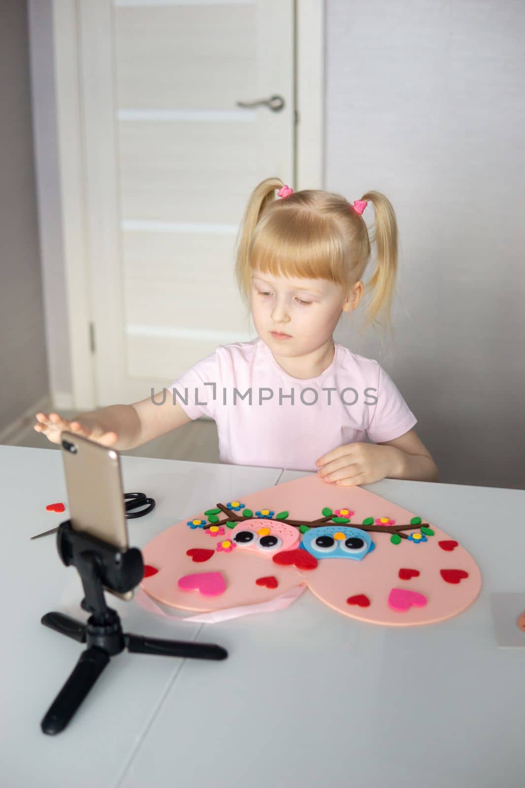 A blogger girl makes a felt craft for Valentine's Day in the shape of a heart. The concept of children's creativity and handmade