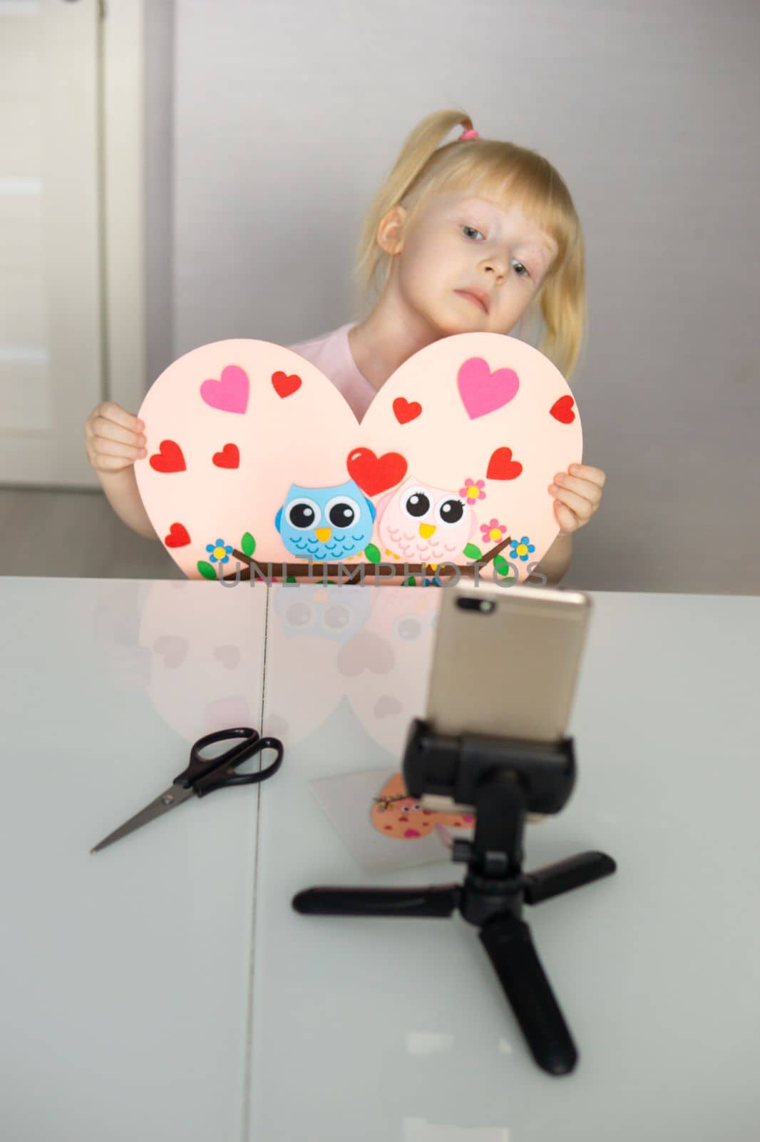 A blogger girl makes a felt craft for Valentine's Day in the shape of a heart. The concept of children's creativity and handmade