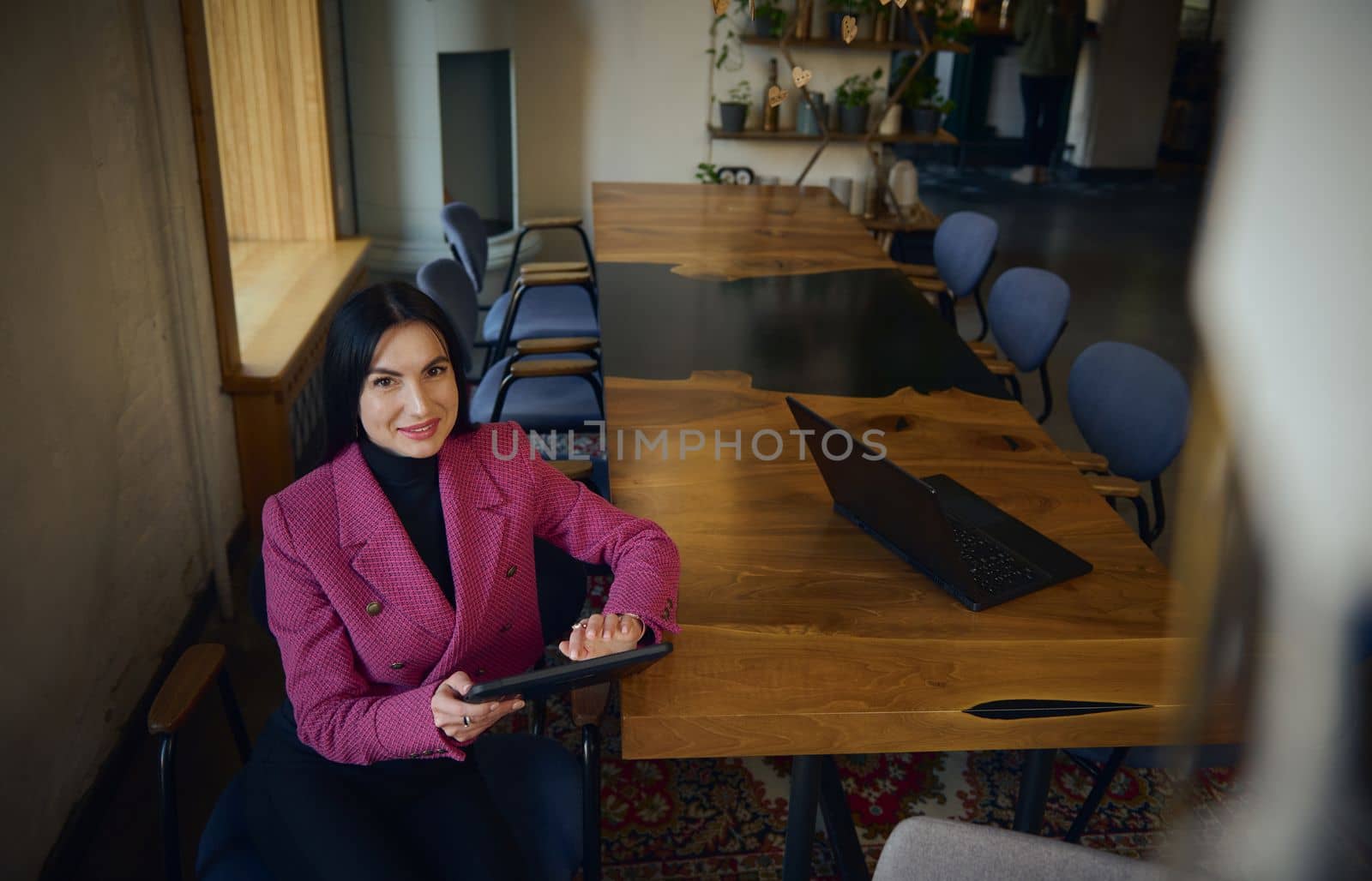 Confident, attractive, successful, goal-oriented middle-aged Caucasian woman, chief executive, business woman sitting with a tablet at the table and waiting for a meeting with partners and investors