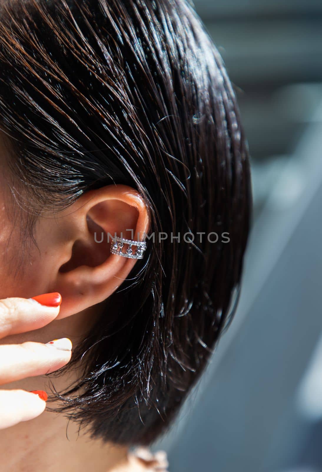 Detail of young woman wearing beautiful silver earring. Women accessories. Selective focus.