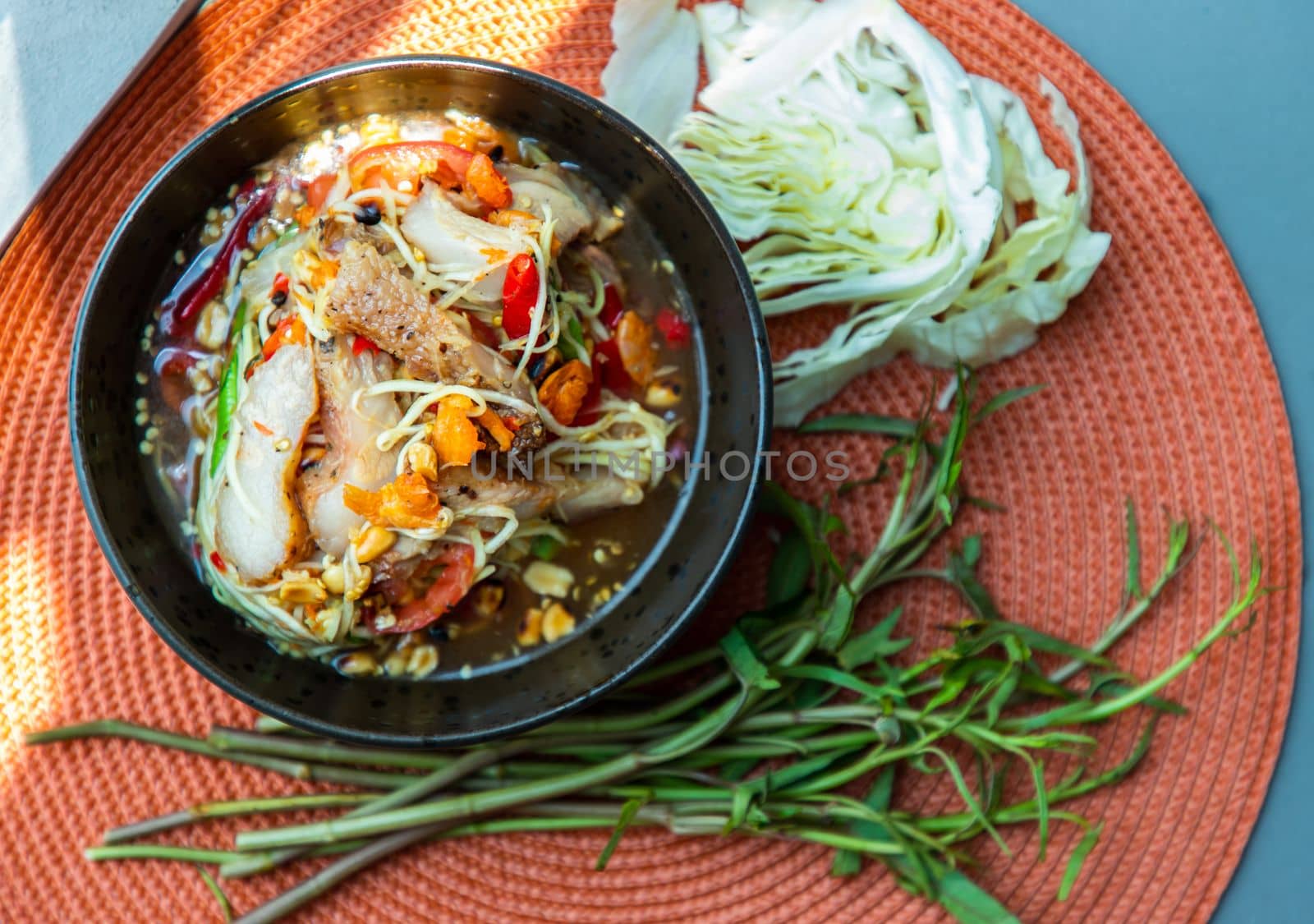 Thai papaya spicy salad (som tum) mix grilled pork neck on ceramic dishes. delicious spicy Thai food, Selective focus.