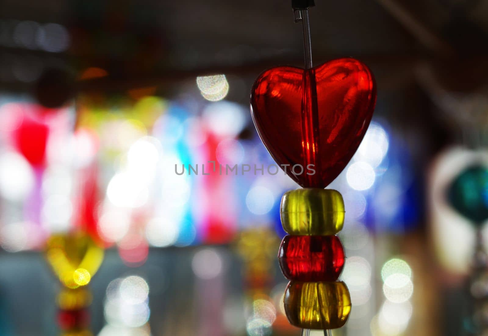 Red translucent heart on a string with a colorful bokeh background