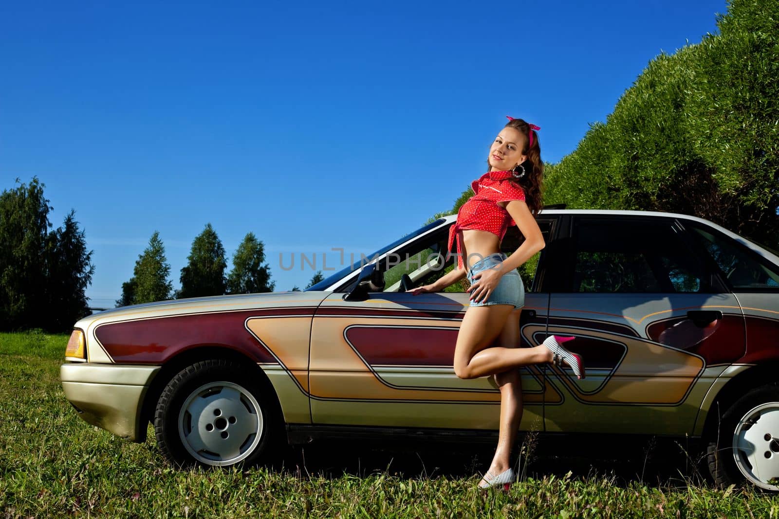 young sexy woman stand near old style car at summer sunset