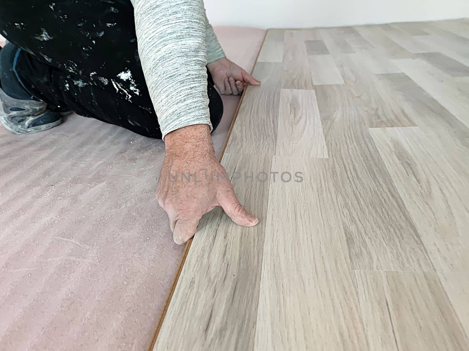 worker laying laminate on the floor close-up by Annado