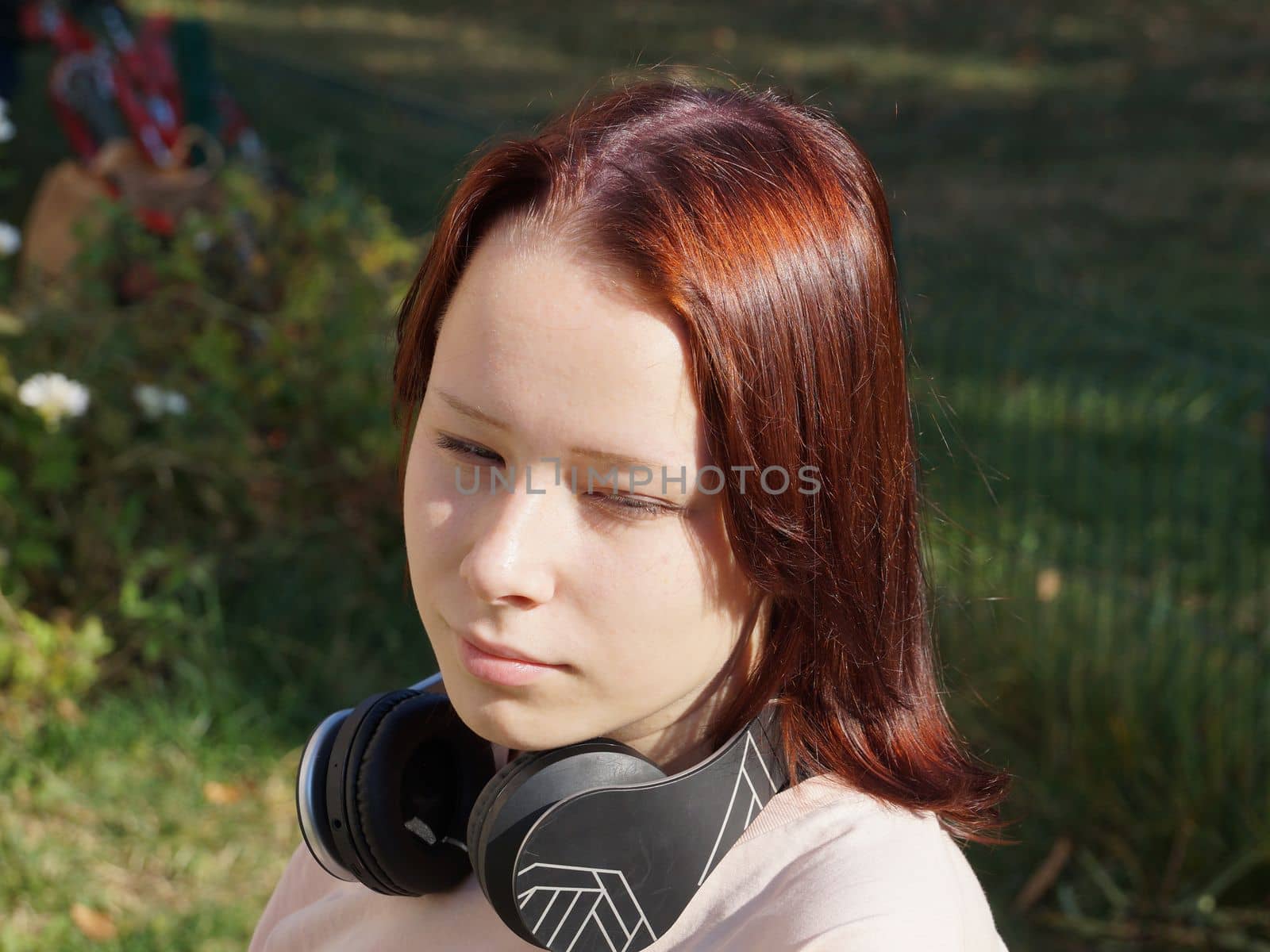 portrait of a red-haired teenage girl with headphones on the background of nature by Annado