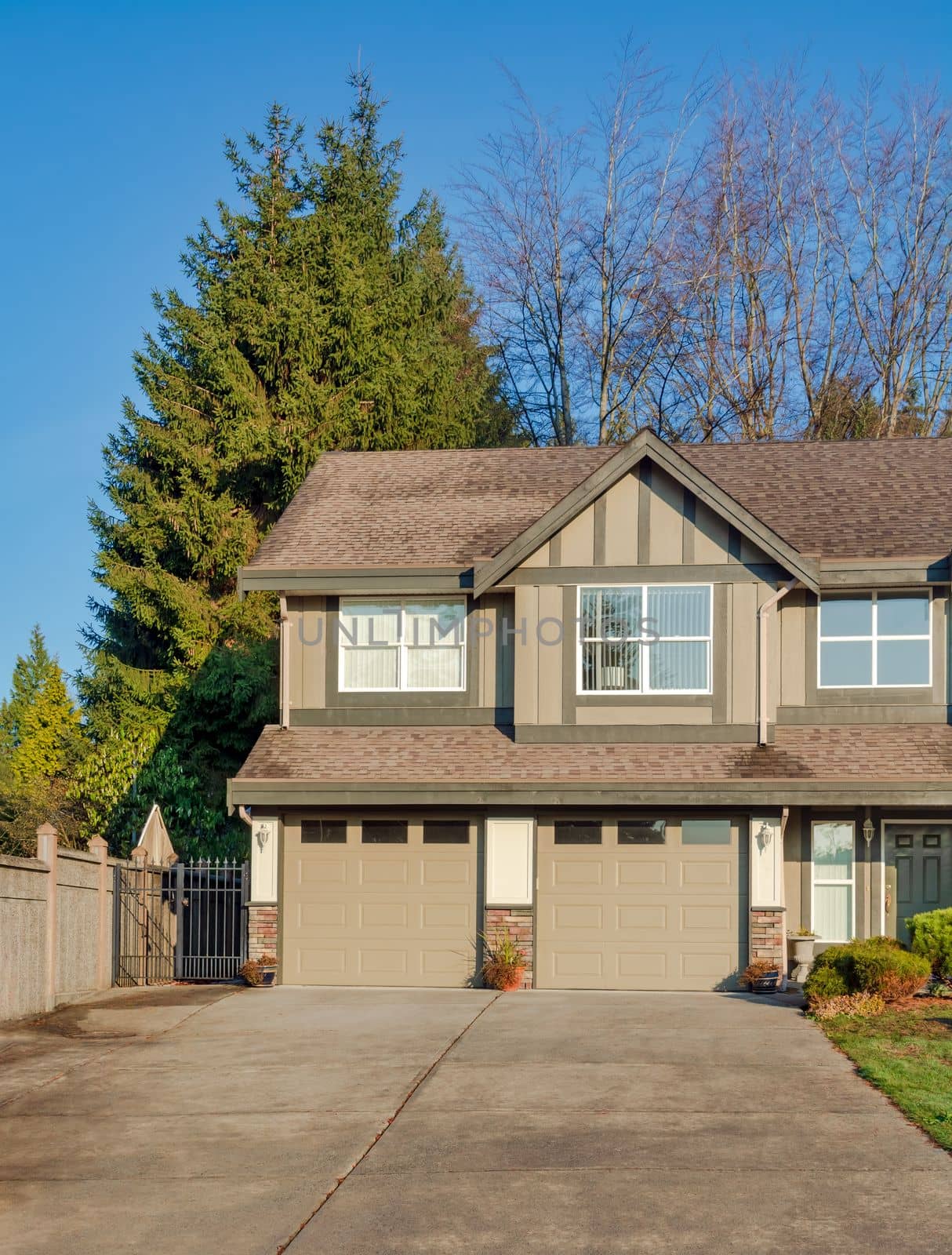 Double garage of residential house with concrete driveway in front. Family house on sunny winter day