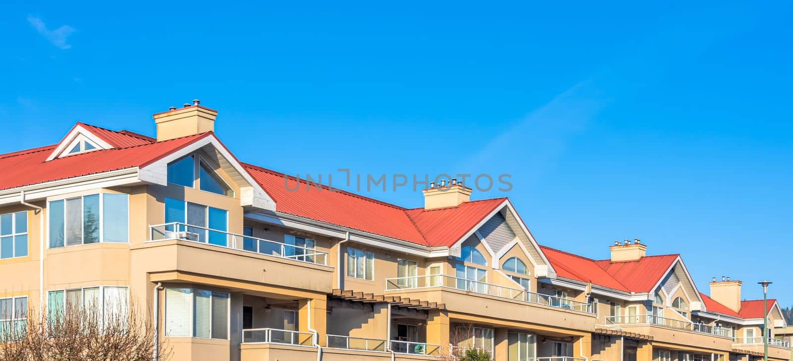 Residential building with red roofs on blue sky background. by Imagenet