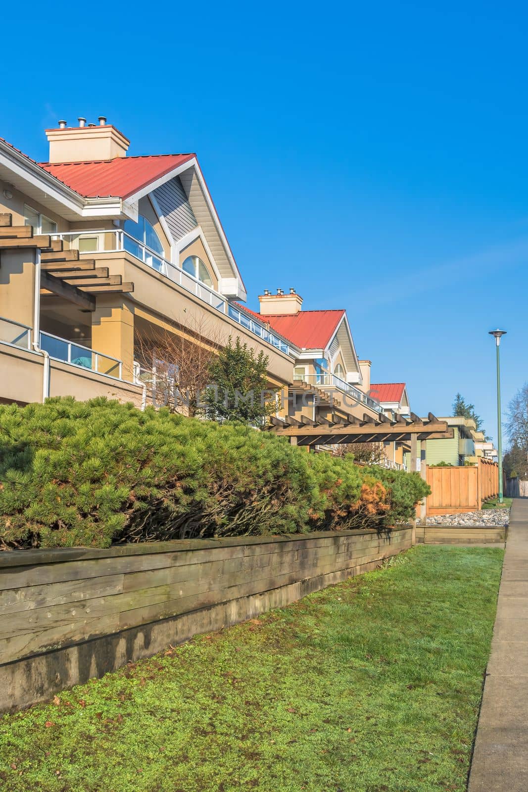 Residential building with red roofs and hedge row on land terrace.