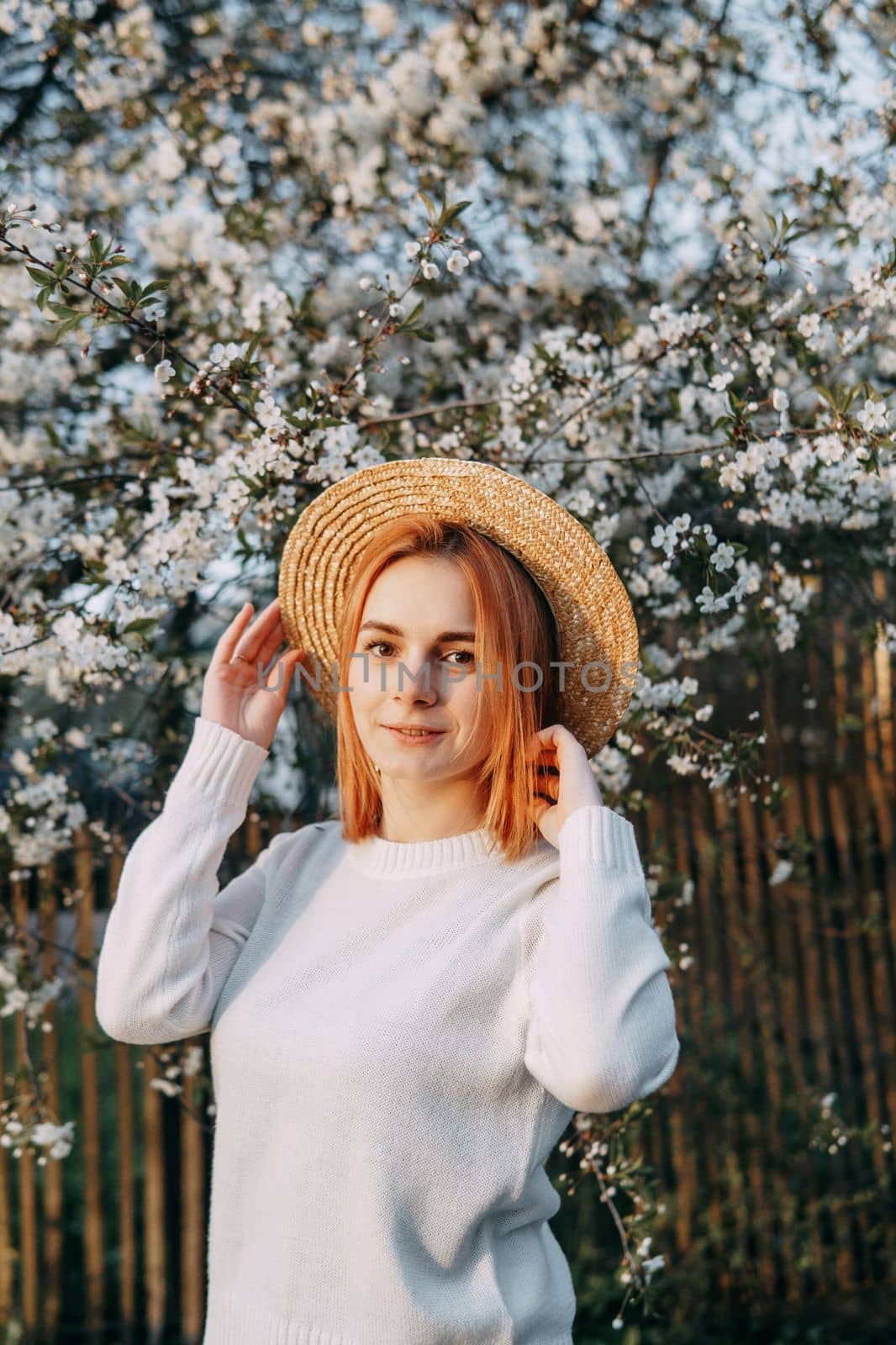 Portrait of a woman in a straw hat in a cherry blossom. Free outdoor recreation, spring blooming garden.