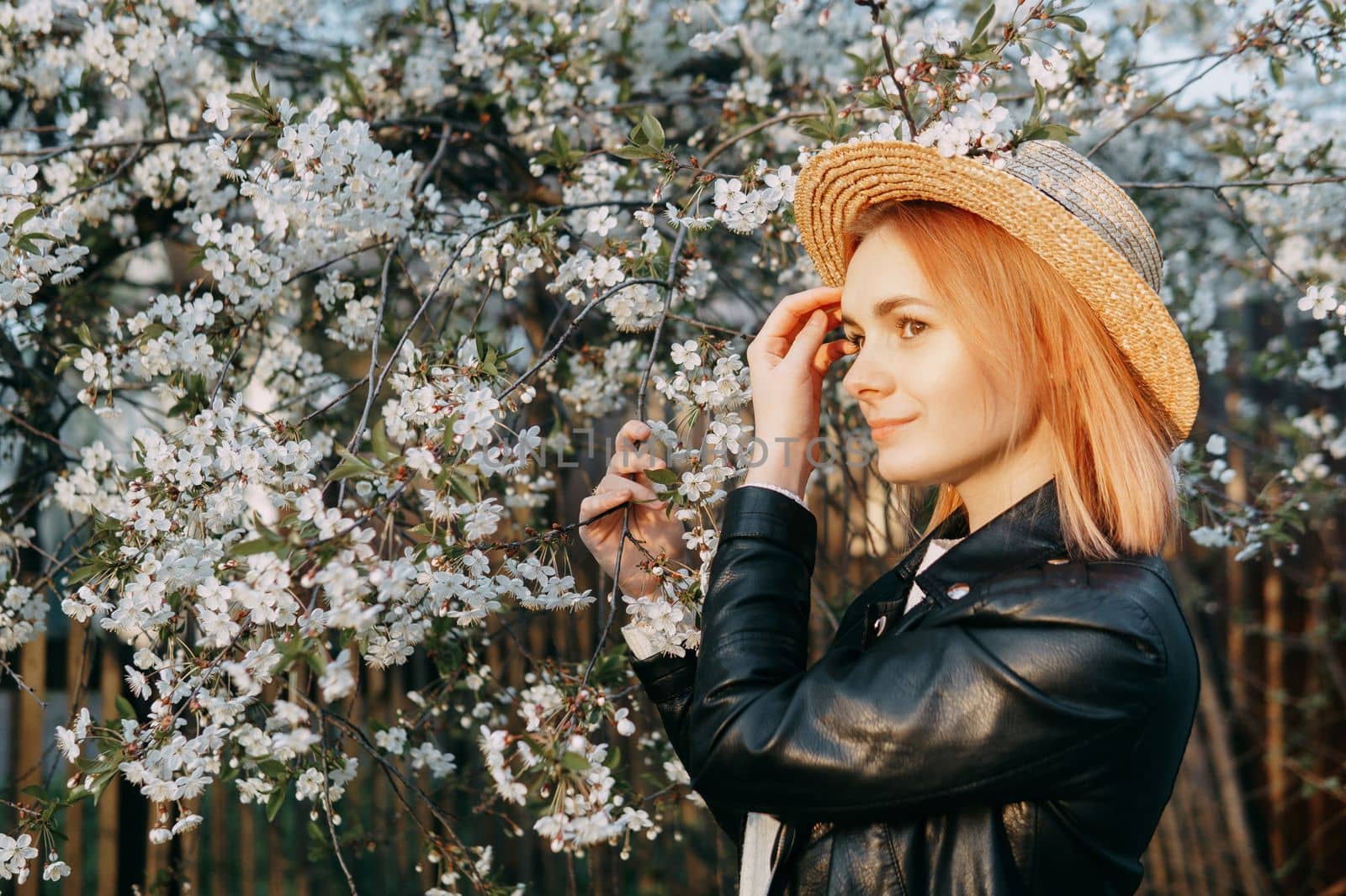 Portrait of a woman in a straw hat in a cherry blossom. Free outdoor recreation, spring blooming garden.