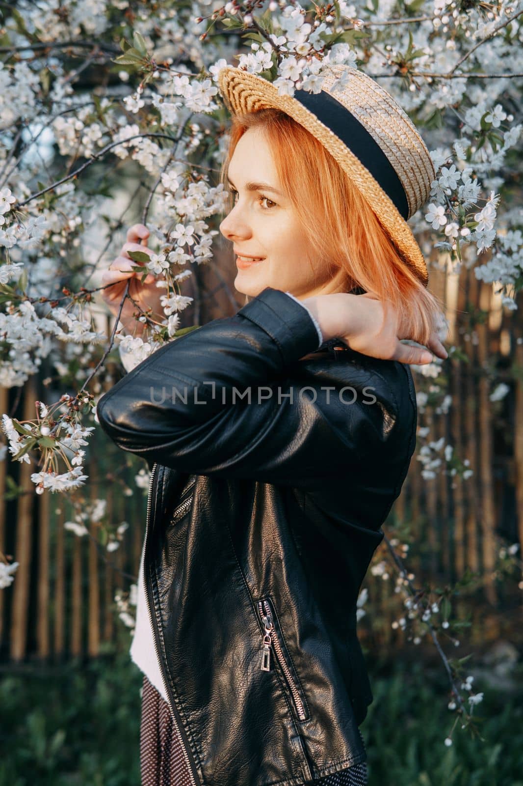 Portrait of a woman in a straw hat in a cherry blossom. Free outdoor recreation, spring blooming garden.