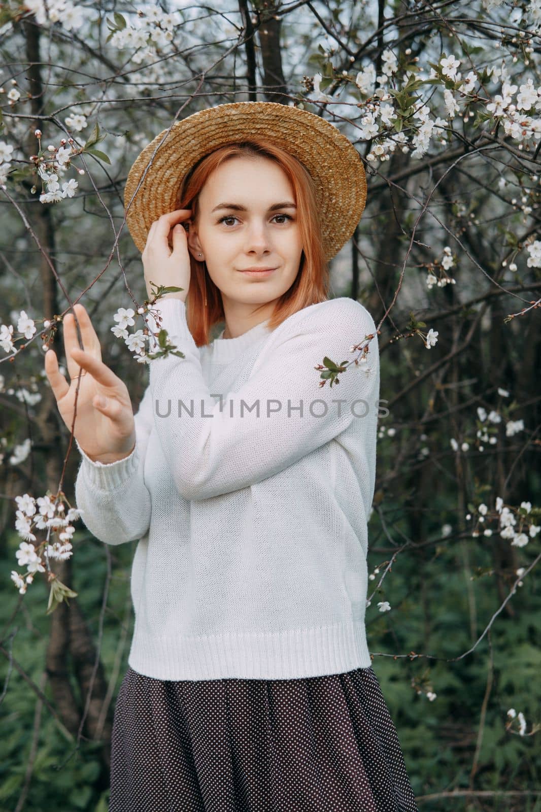 Portrait of a woman in a straw hat in a cherry blossom. Free outdoor recreation, spring blooming garden