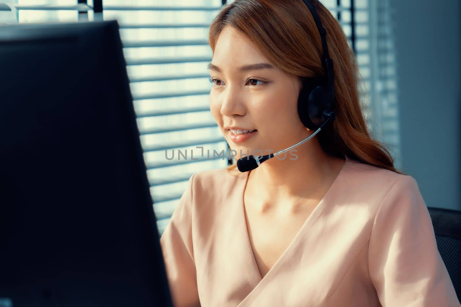 Competent female operator working on computer and while talking with clients. Concept relevant to both call centers and customer service offices.