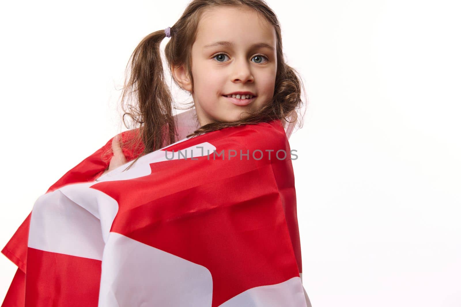 Canadian citizen, lovely little girl wrapping flag of Canada, celebrates Independence Day, Dominion Day, 1st July. Human rights and freedoms, isolated on white background with space for your promotion