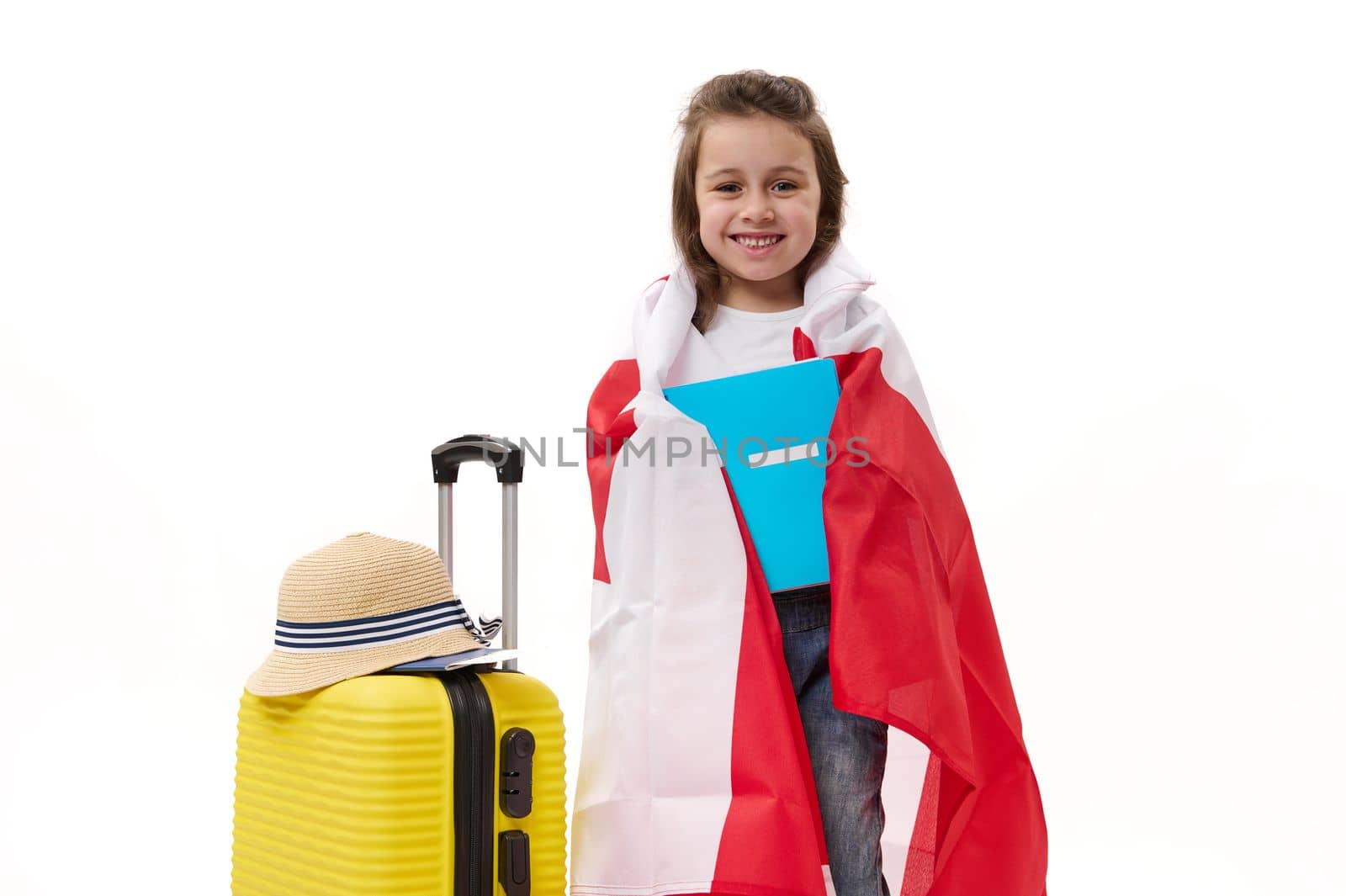Adorable smart preschooler child, a lovely little girl with textbook, wrapped in Canadian flag, happy to immigrate to Canada to study, isolated on white background with free space for your advertising