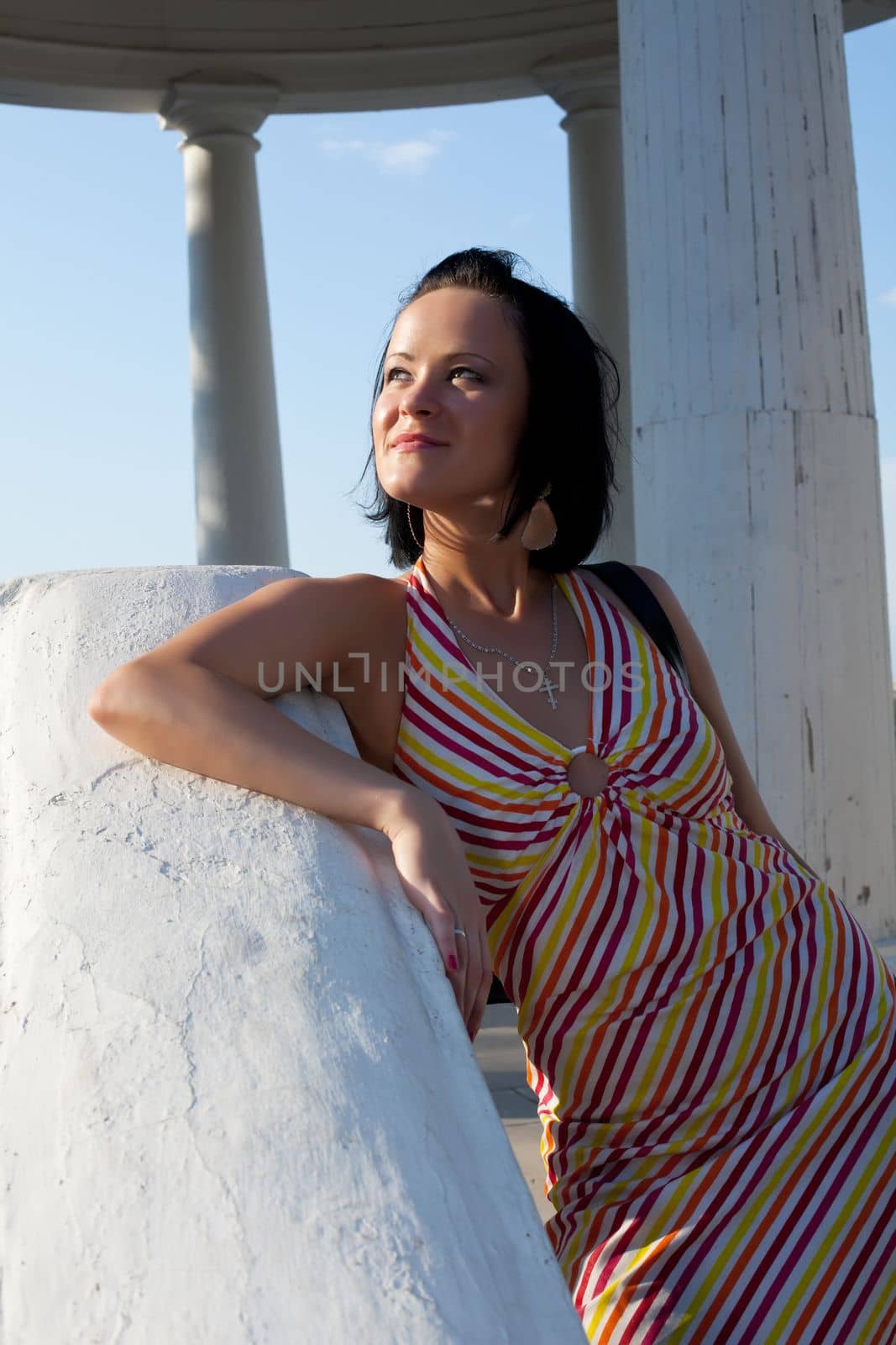 young woman in summer park at sunset and white rotunda