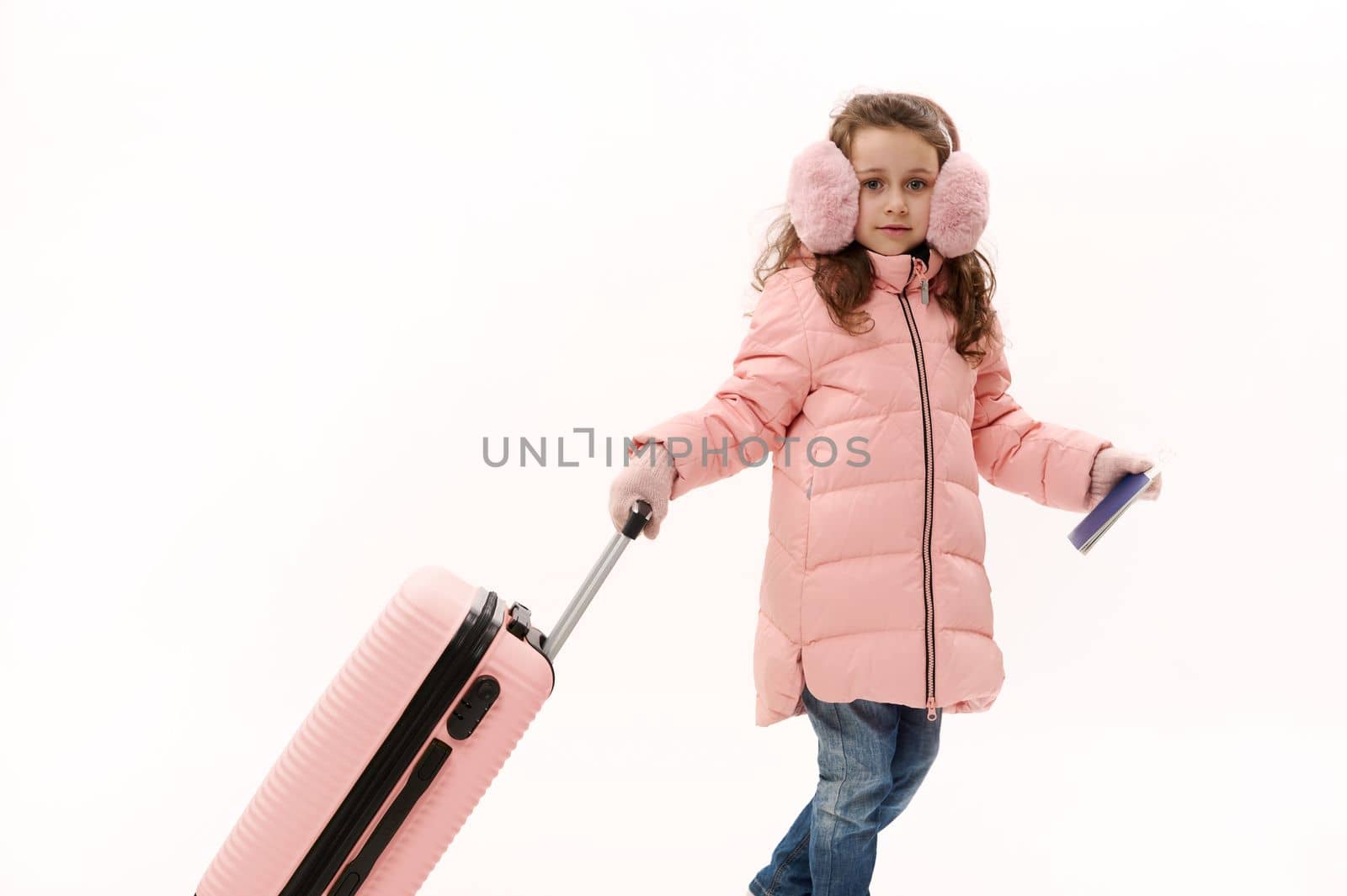 ue jeans and plush earmuffs, walking with a boarding pass and a suitcase on a white background. Kids traveling on weekend getaway