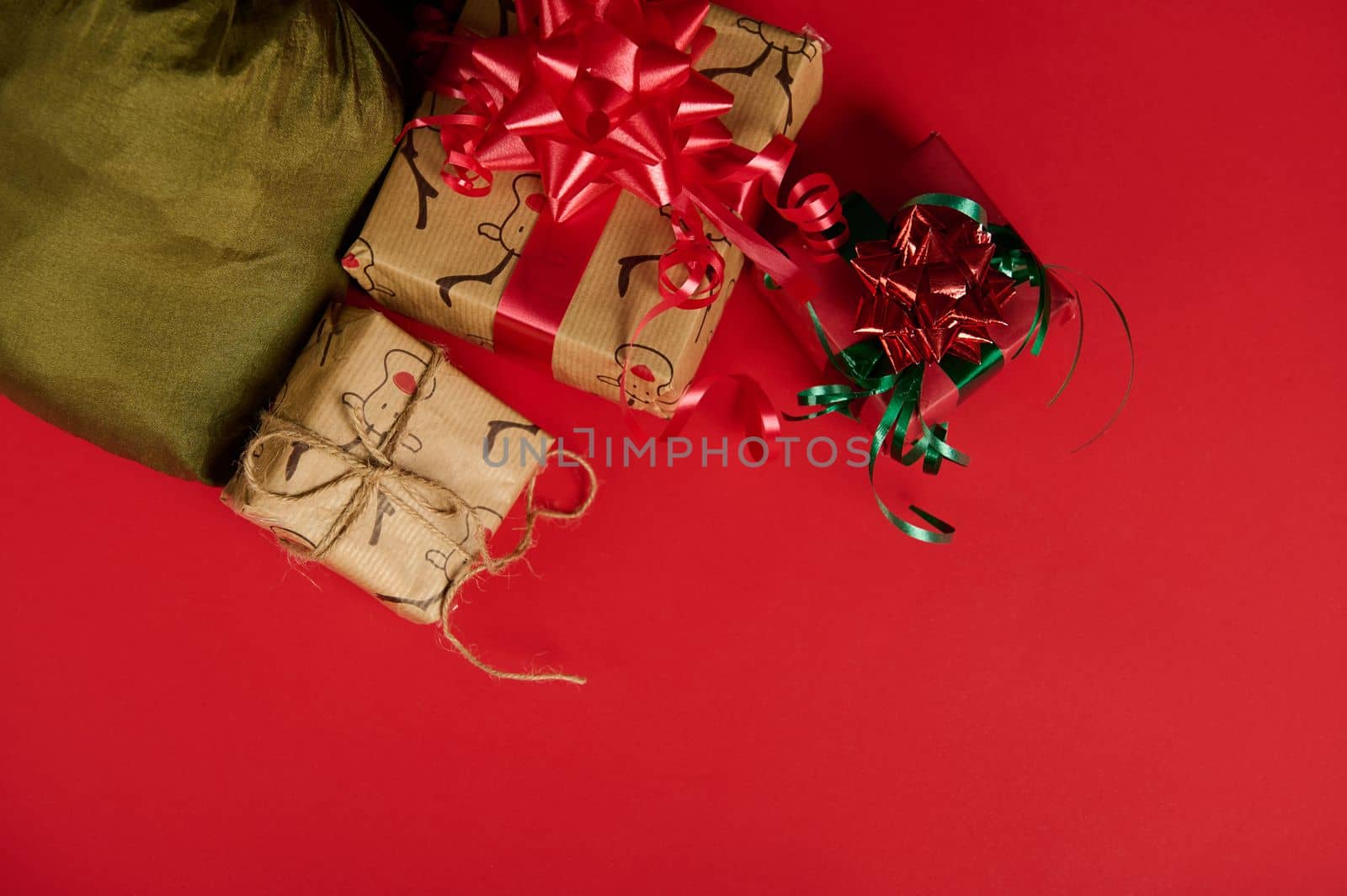 In the corner on a red background are boxes of Christmas gifts wrapped in stylish wrapping paper and tied with decorative bows and ribbons, and a green satin bag. New Year's event. Xmas. Boxing Day