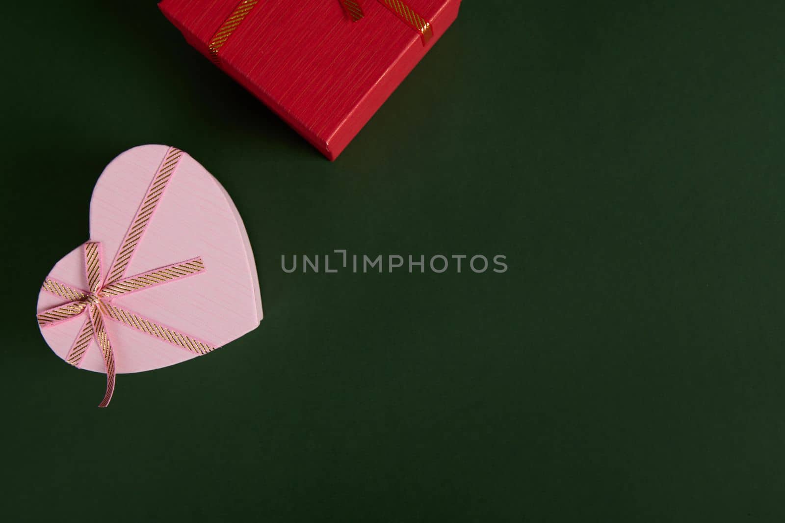 Still life with a heart shaped pink red gift boxes on a green background. Boxing DAY. Saint Valentine's and Women's Day. Copy advertising space