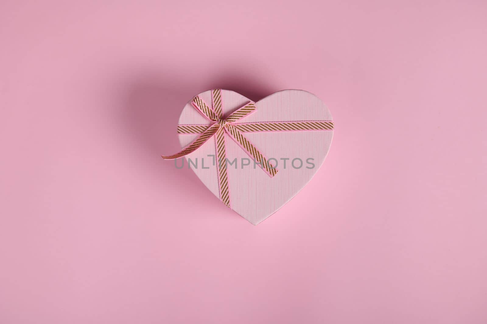 Flat lay with Valentine's Day love gift, in a heart shaped box. February 14. Still life on pink background with copy ad space. Romantic present for Women's Day in March 8