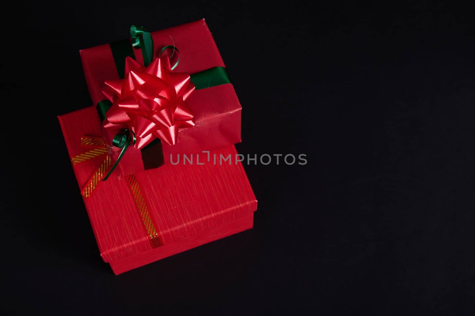 Top view of stacked red gift boxes with tied bows for Christmas, isolated on black background with copy advertising space. Christmas gift boxes, New Year Gift Boxes. Boxing Day. Present. Surprise