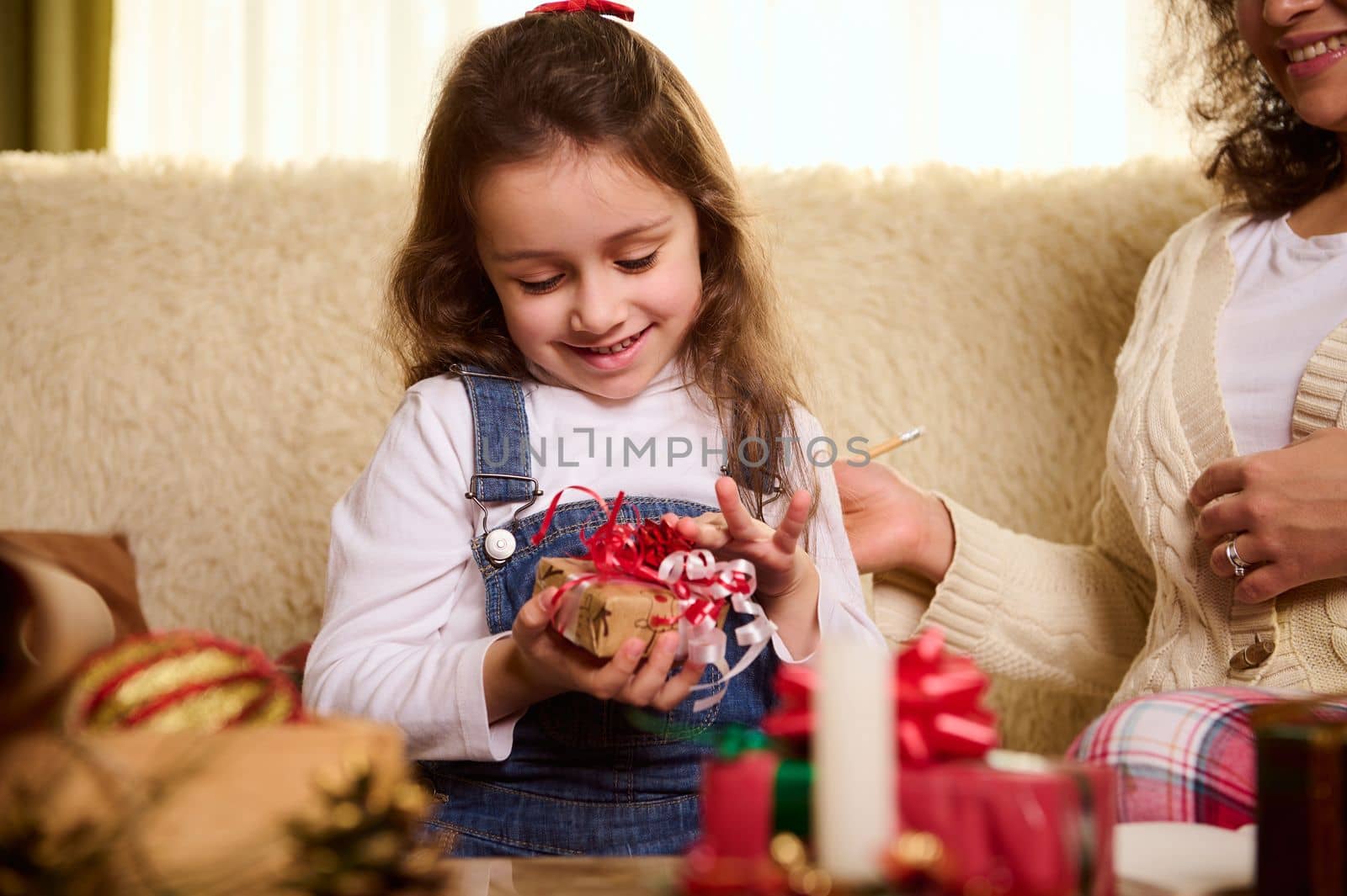 Caucasian delightful cute baby girl rejoices at a Christmas present. Enjoying winter holiday. Magical festive atmosphere at home. Boxing Day. Preparing for Xmas and New Year. Happy carefree childhood