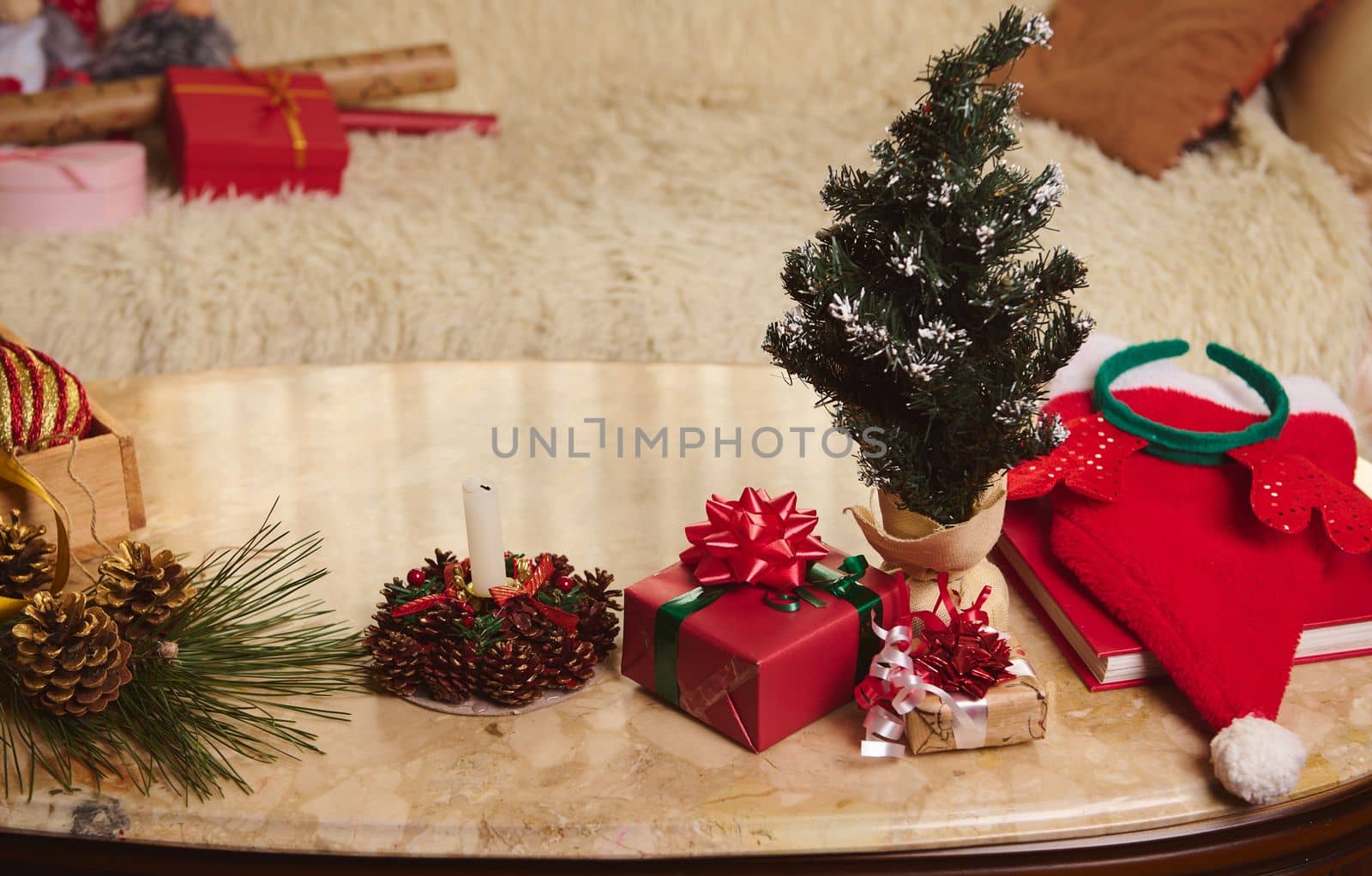 View from above of a marble table with happy gifts, decorated Christmas tree, lighted candle. New Year preparations. Happy winter holidays. Magic mood. Wiring shot