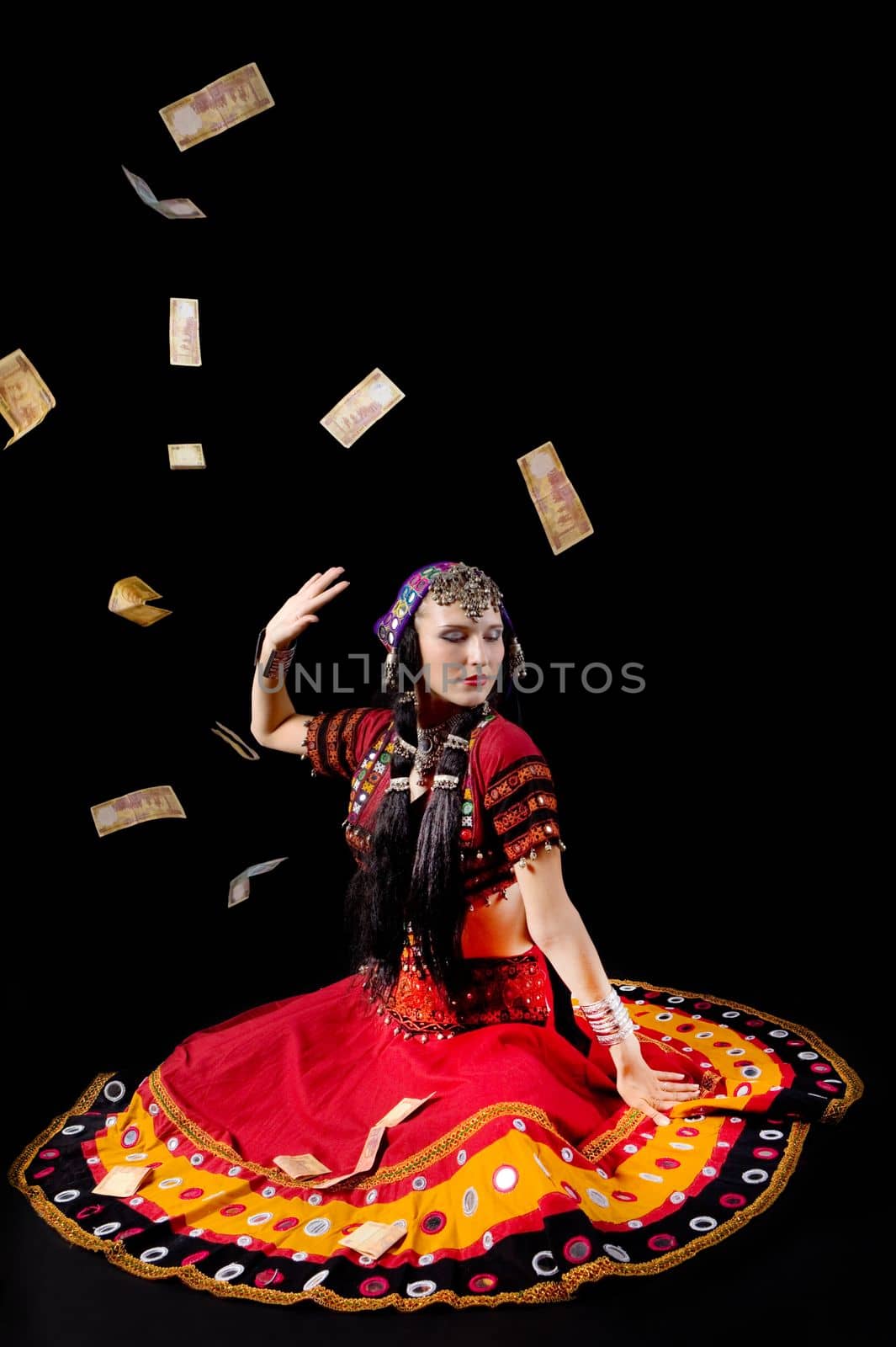 woman in traditional indian costume againist falling money studio shot