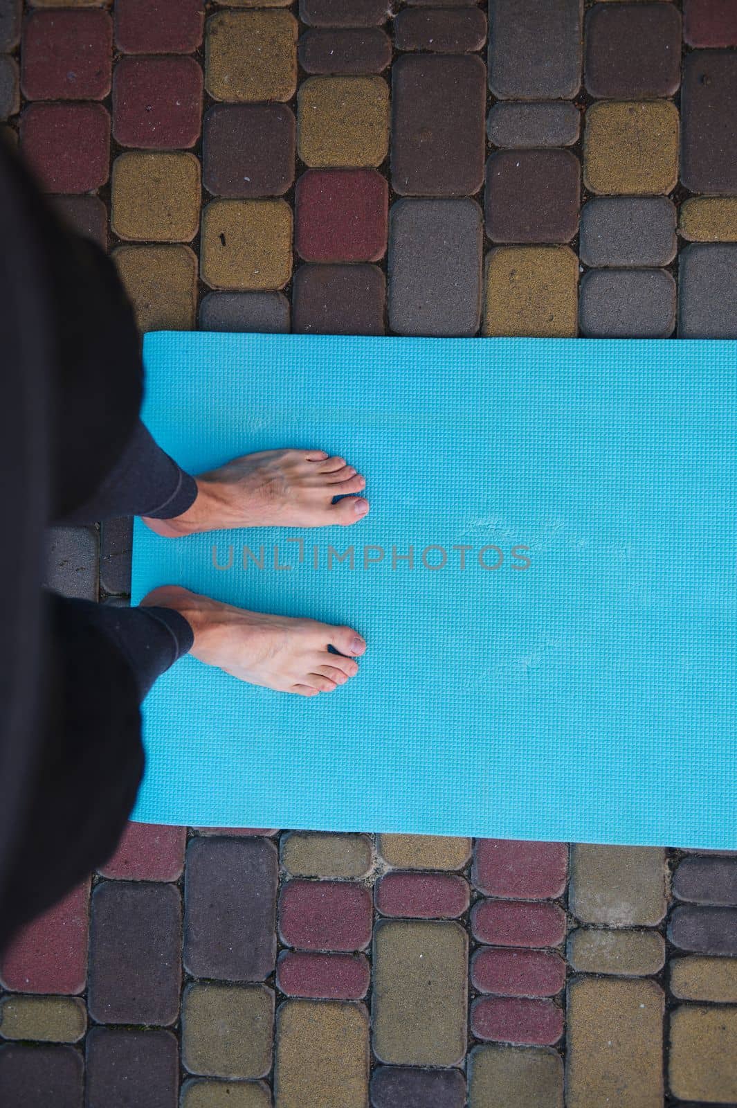Directly above unrecognizable man, yogi, athlete practicing yoga, standing barefoot on the fitness mat. Copy ad space by artgf