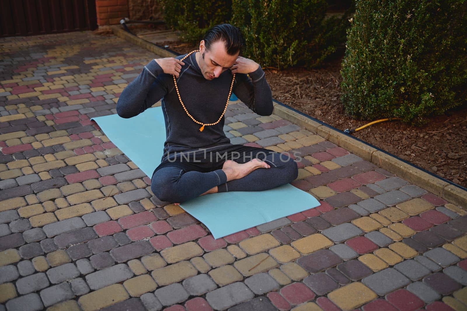 Portrait of a yogi, sitting on a fitness mat during a yoga practice. Healthy and active lifestyle. Mindfulness. Awakening. Enlightenment. Spiritual growth. Healthy lifestyle. Body conscious