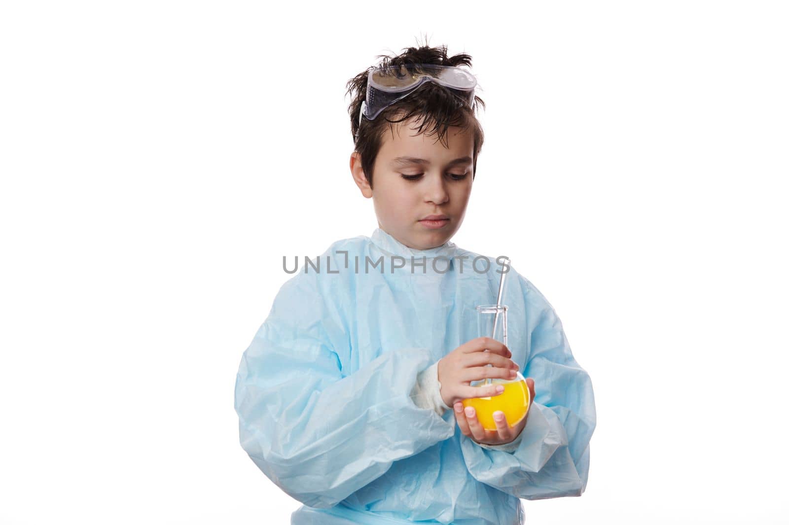 Confident smart pupil, a young chemist scientist teenage boy in labwear, mixing chemical solution in a laboratory flask with glass stick, isolated over white background. Chemistry. Science. Education