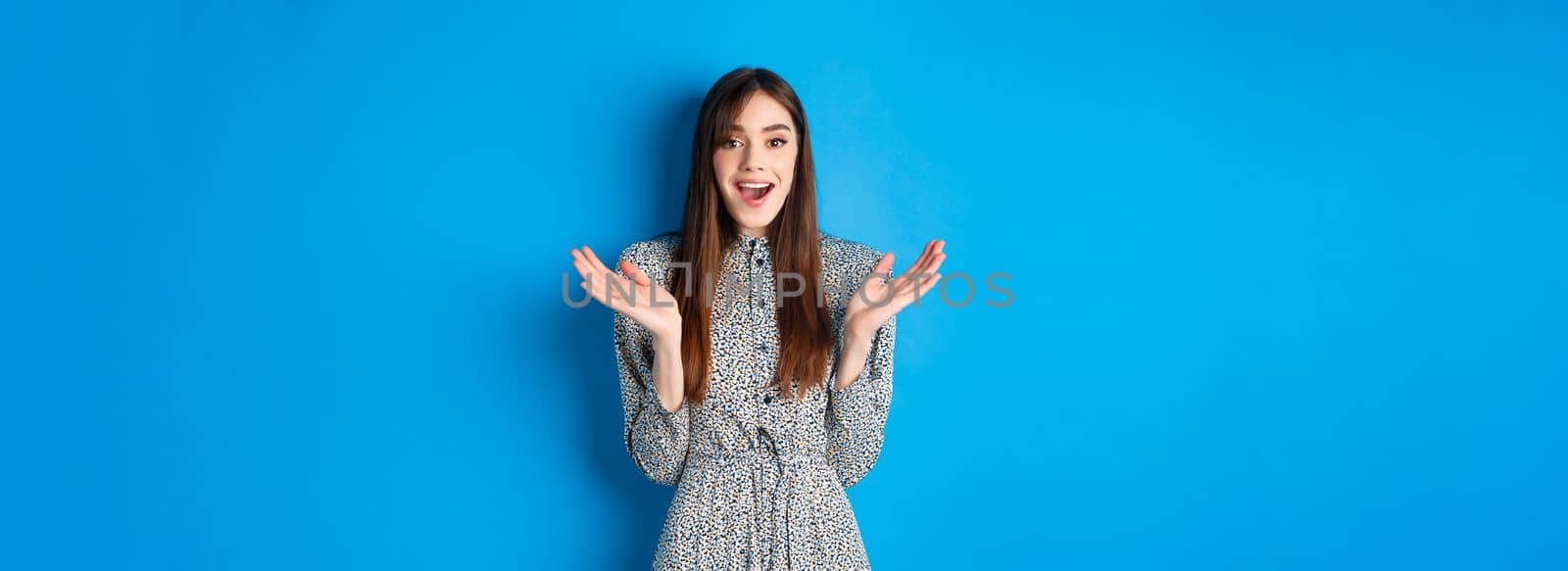 Excited beautiful woman clap hands and congratulate you, praising nice work, applause at camera and smiling, standing on blue background.