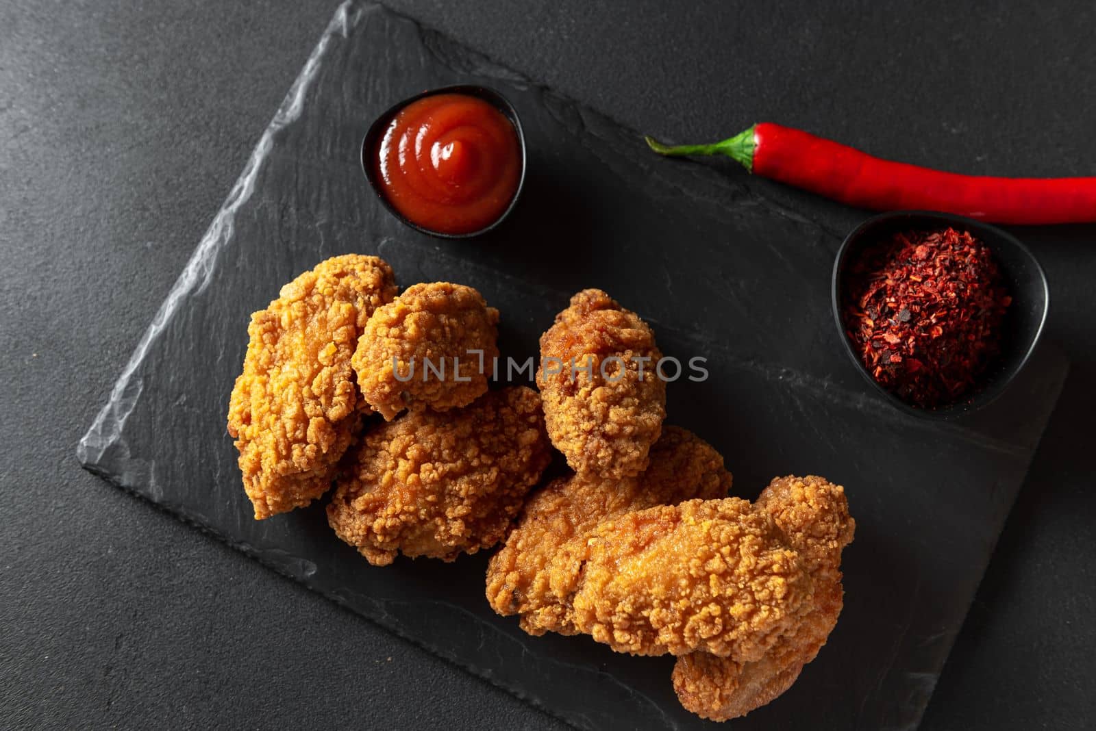 Spicy fried chicken in crispy breading. Black background. Top view. Copy space.