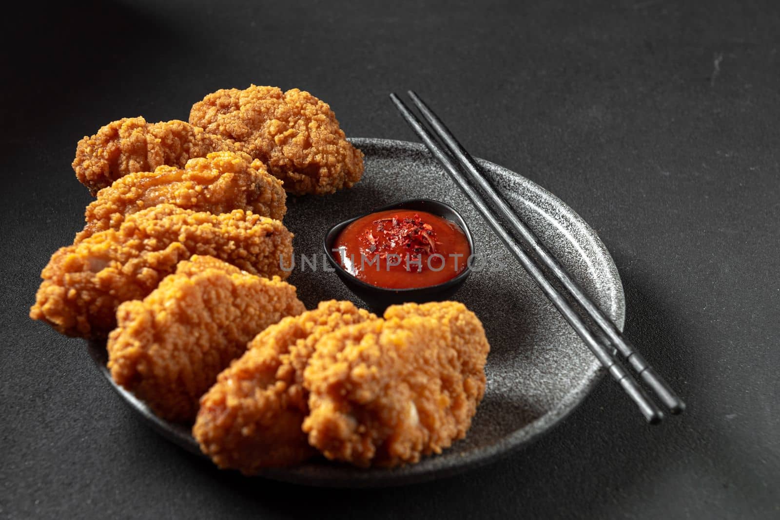 Asian meat deep-fried, breaded in oil in a plate on a dark stone background with copy space. Top view, flat plan.