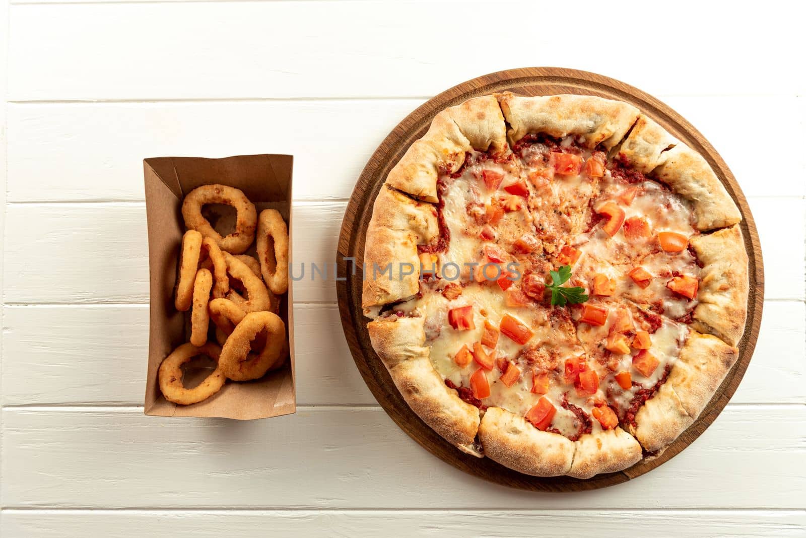 Delivery Concept. Neapalitan pizza with tomatoes on white with appetizers. Set pizza and appetizers side by side on white top view by gulyaevstudio