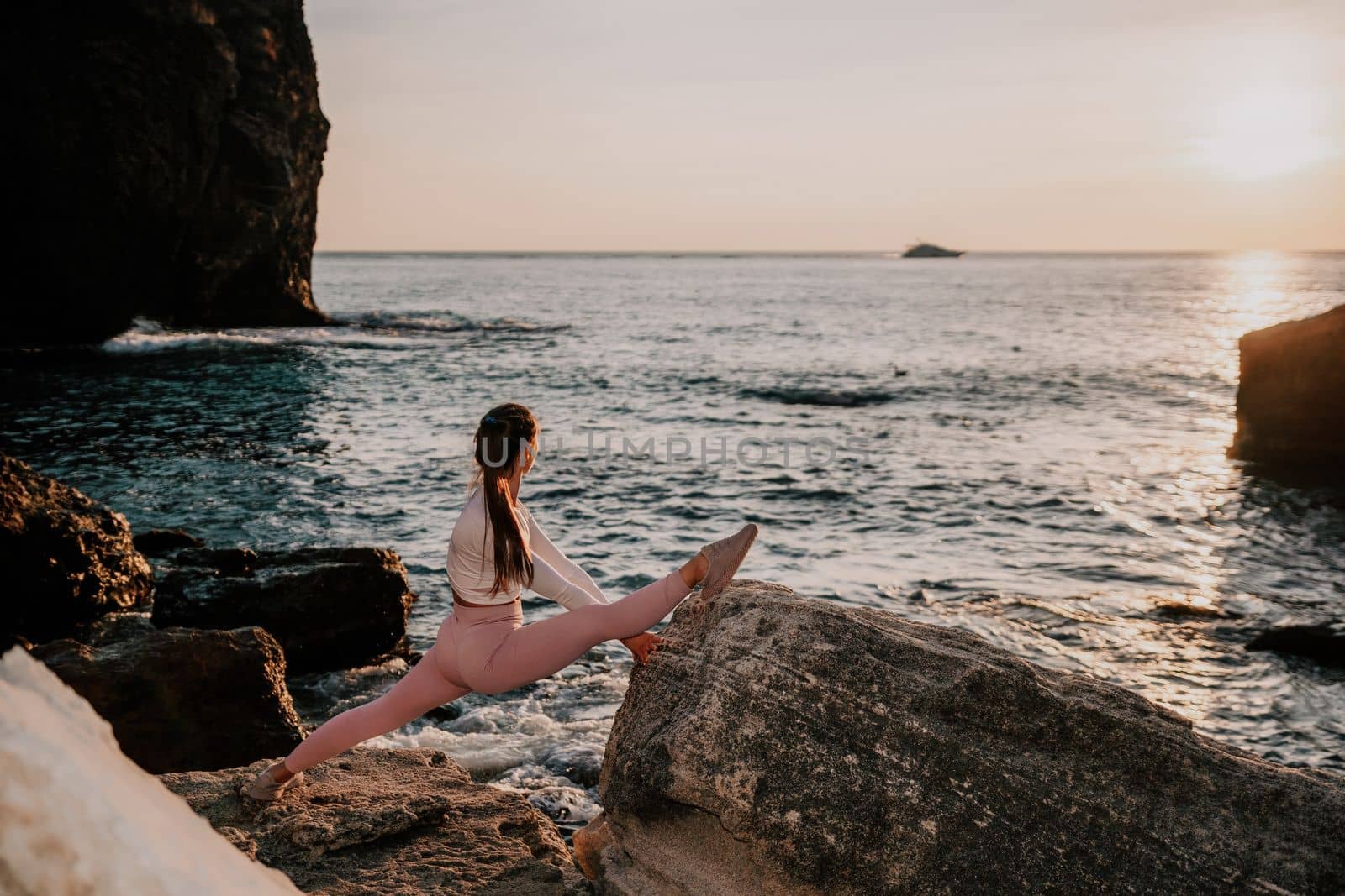 Young woman with black hair, fitness instructor in pink sports leggings and tops, doing pilates on yoga mat with magic pilates ring by the sea on the beach. Female fitness daily yoga concept