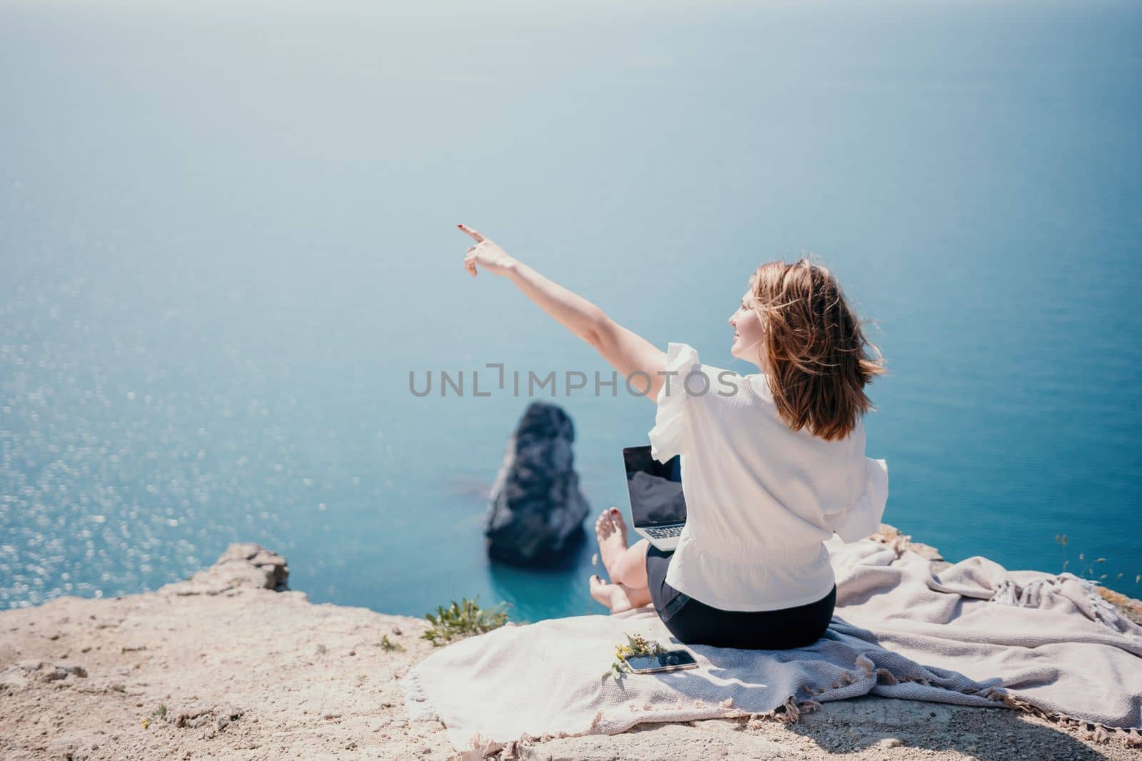 Woman sea laptop. Successful business woman working on laptop by the sea. Pretty lady typing on computer at summer day outdoors. Freelance, digital nomad, travel and holidays concept. by panophotograph